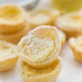 Mini Lemon Chess Pies stacked on top of each other with lemons in the background