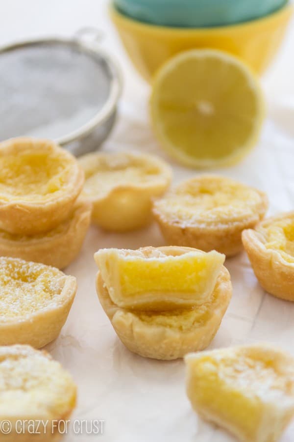 Mini Lemon Chess Pies stacked on top of each other with lemon and yellow bowl in the background 