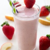 Strawberries Wild Jamba Juice Copycat In a tall clear glass with a strawberry on the rim of the glass and two straws in the drink