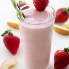 Strawberries Wild Jamba Juice Copycat In a tall clear glass with a strawberry on the rim of the glass and two straws in the drink