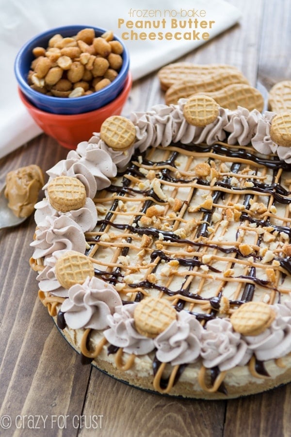 This No-Bake Frozen Peanut Butter Cheesecake on a brown board with blue and orange bowl with nuts in them