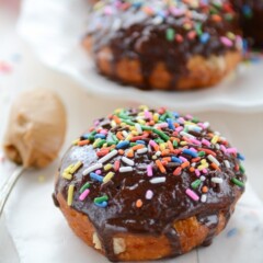 fried doughnut with chocolate frosting and sprinkles on white plate