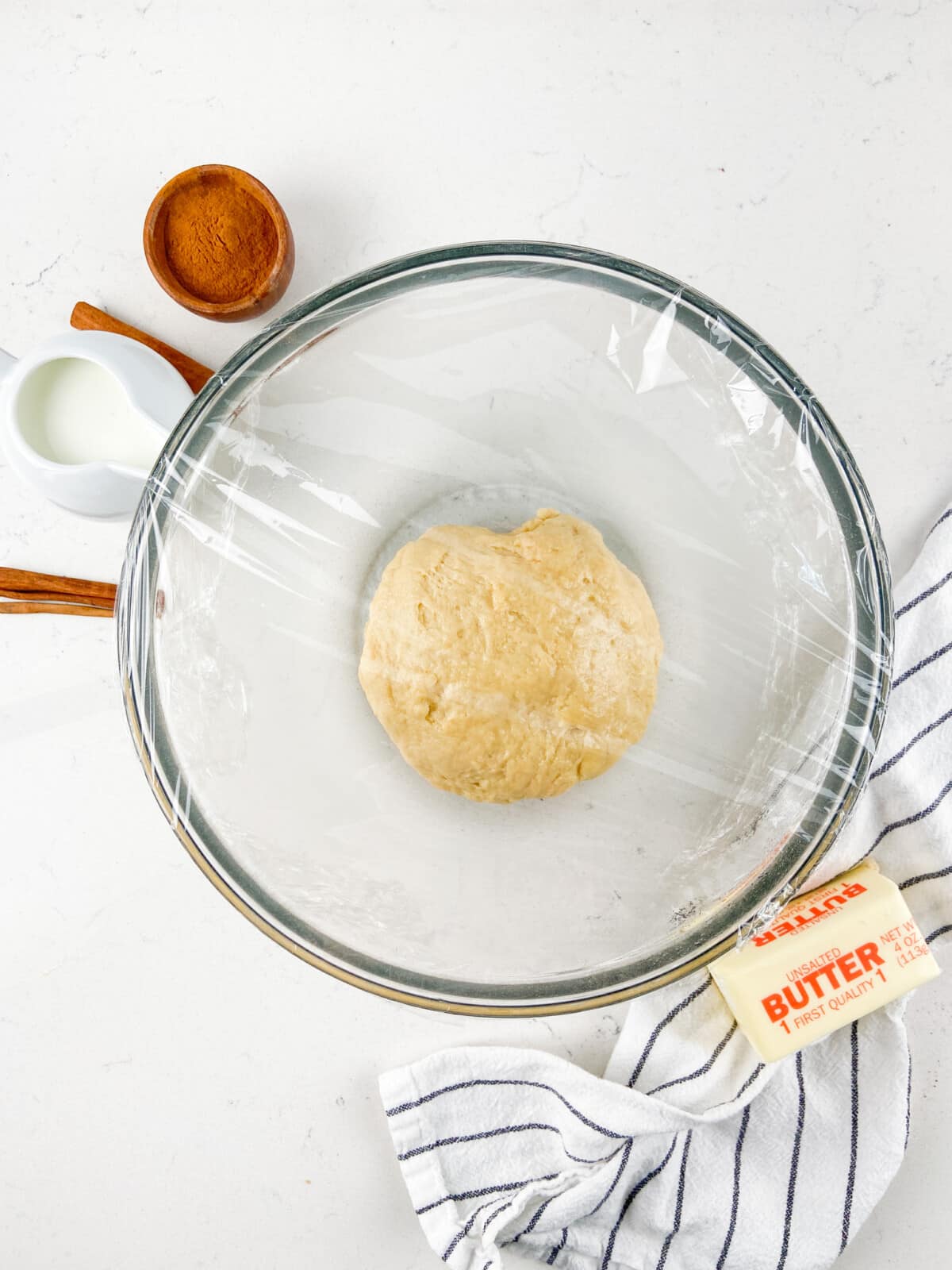 bread dough in bowl with plastic wrap.