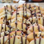 sliced apples drizzled with caramel and chocolate on cutting board