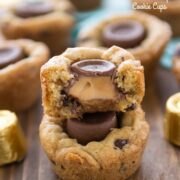 stack of cookie cups on wood table with one cut in half and caramel oozing out