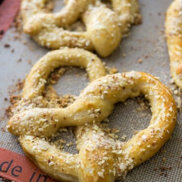 soft pretzel with almond topping on cookie sheet
