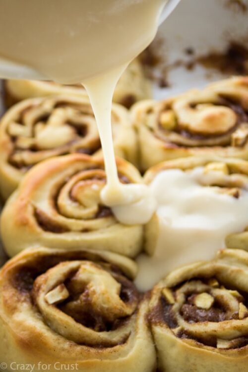 6 cinnamon rolls having icing poured on them