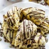 scones on a white plate with chocolate drizzled on top.