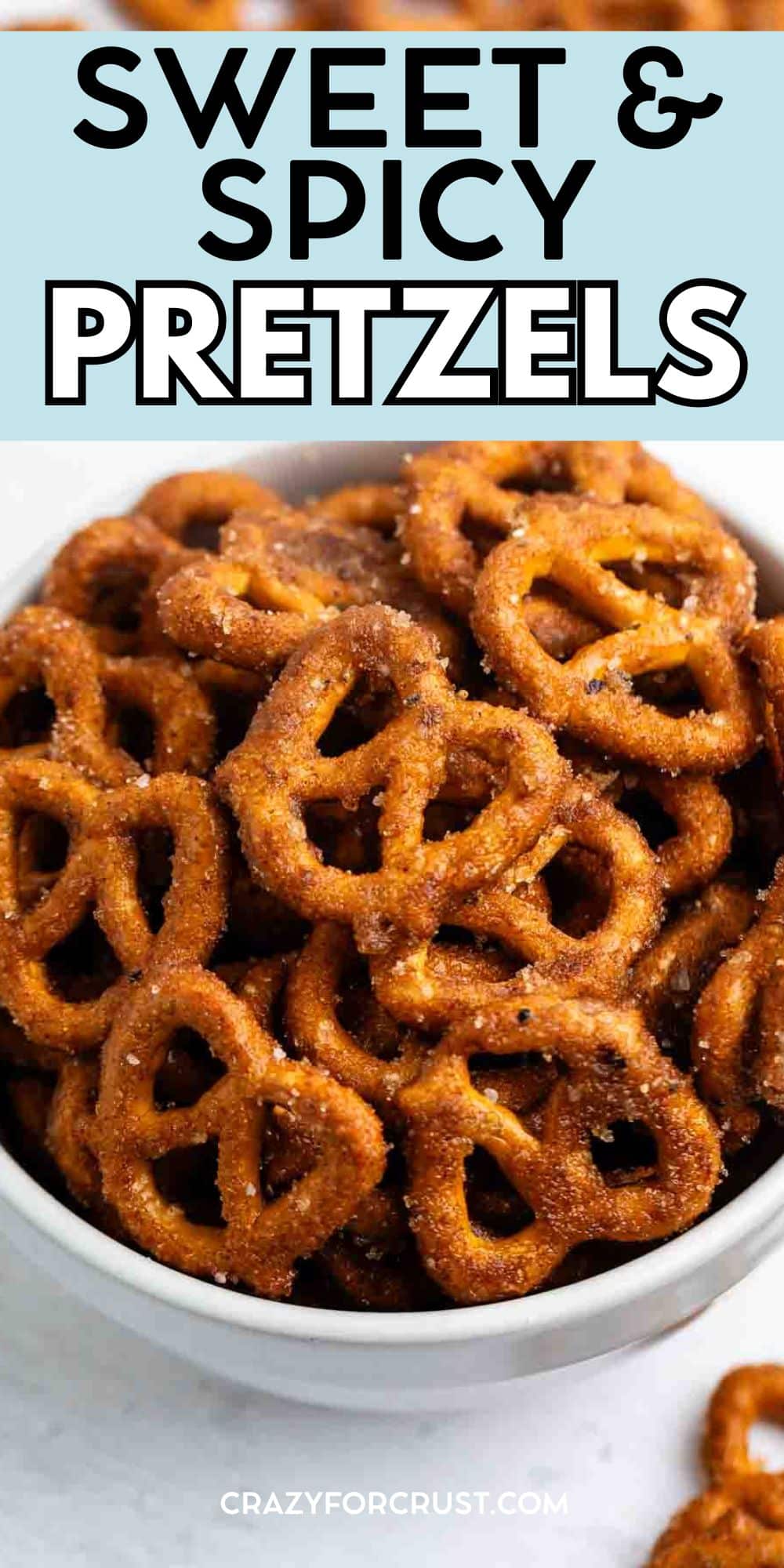 A white bowl filled with golden-brown sweet and spicy pretzels coated in a flavorful seasoning. Text above the bowl reads, SWEET & SPICY PRETZELS.