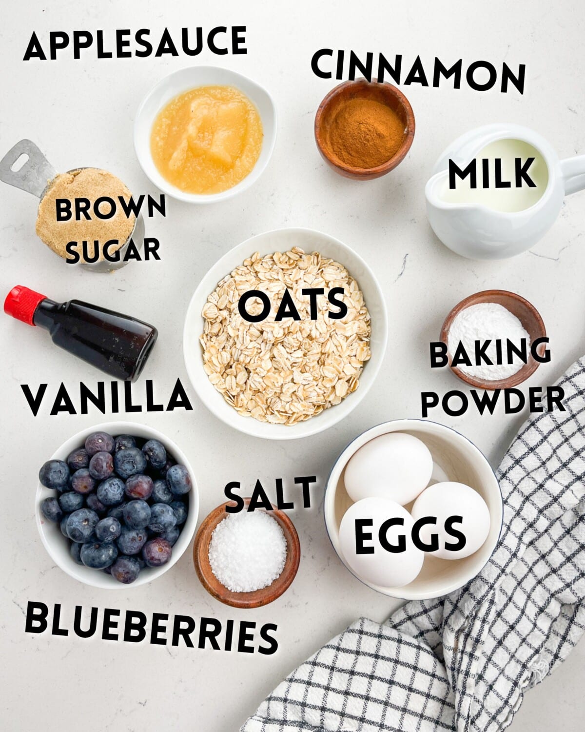ingredients on baked blueberry oatmeal laid out on a white marble counter.