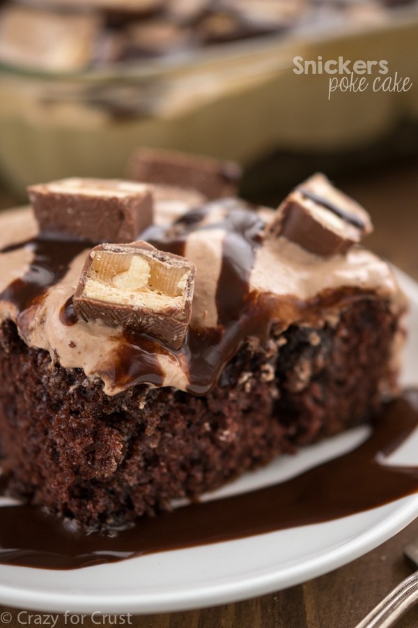 Snickers Poke Cake filled with caramel and peanuts and topped with a nougat frosting!