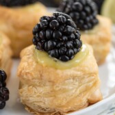 Close up shot of blackberry key lime tarts on a white plate with napkin underneath