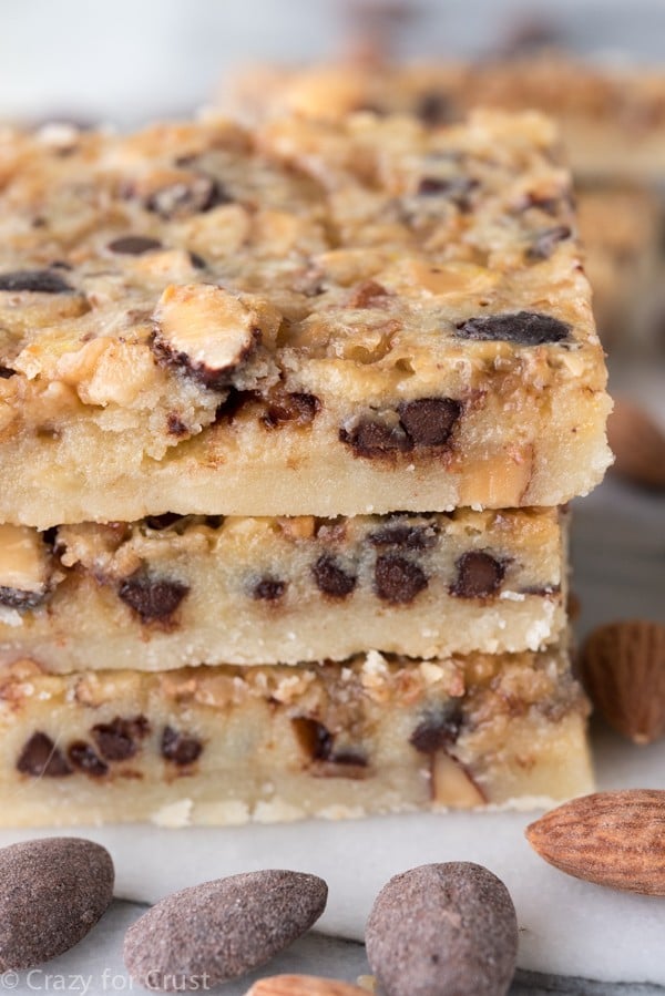 Chocolate Toffee Almond Shortbread Bars stacked on top of each other with almonds all around