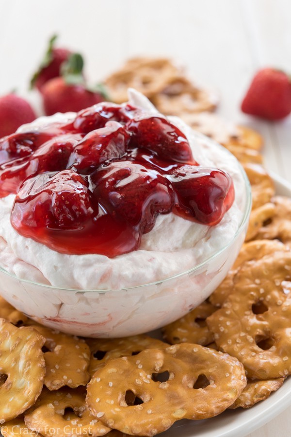 Strawberry Pretzel Salad Dip in a clear bowl with pretzels around it 