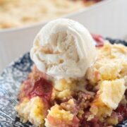 Cherry peach dump cake on a blue and white plate with ice cream on top