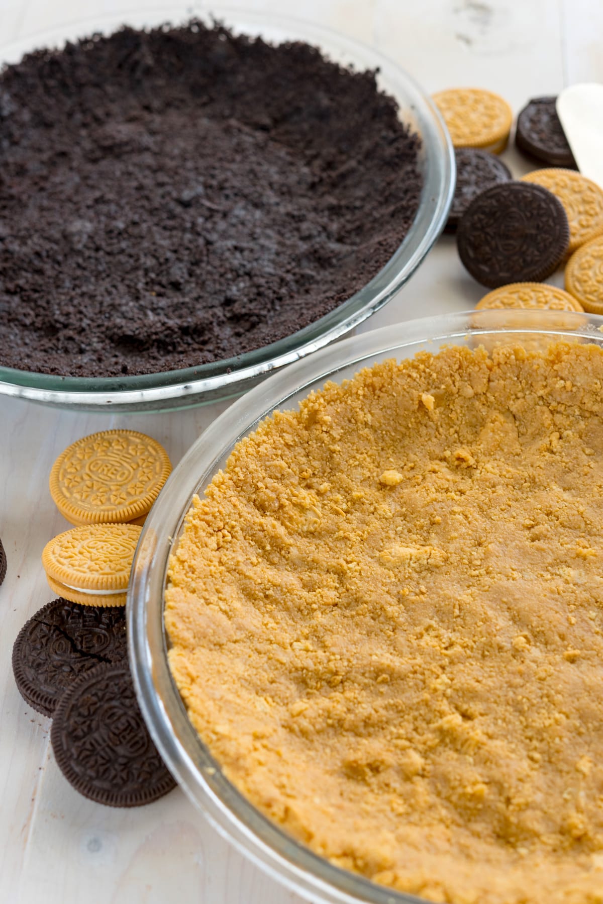 regular and golden oreos crushed into a pie crust form in clear pie pans.