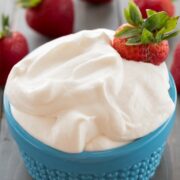 Marshmallow whipped cream in turquoise dish surrounded by strawberries