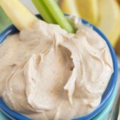Skinny peanut butter dip in small blue bowl with celery