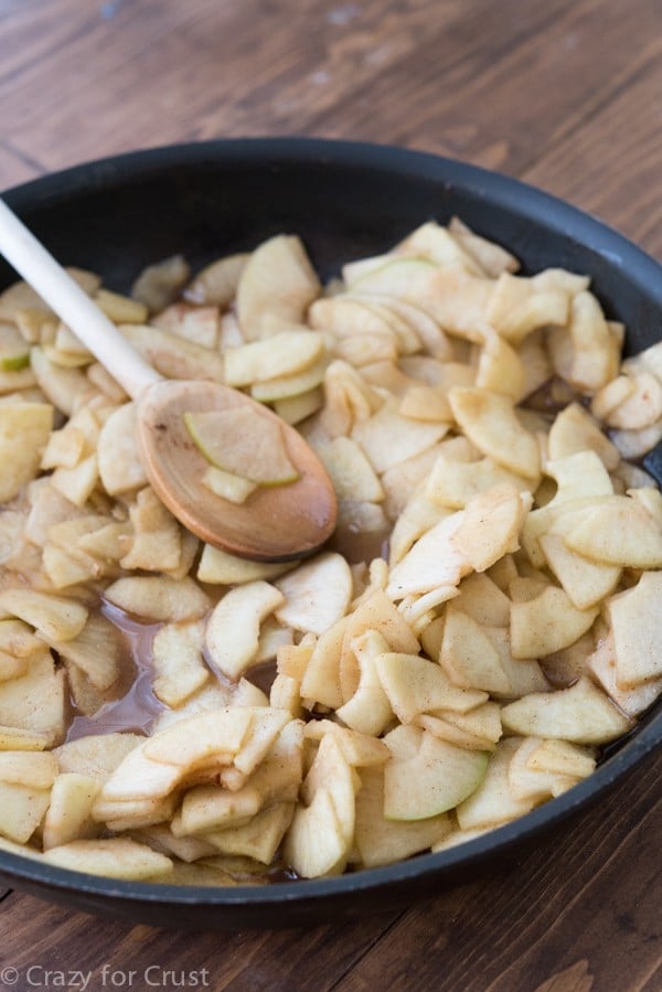 Process shot of cooking sliced apples in shallow pan