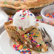 Slice of Cake Batter Cookie Pie on a white plate and ice cream on top