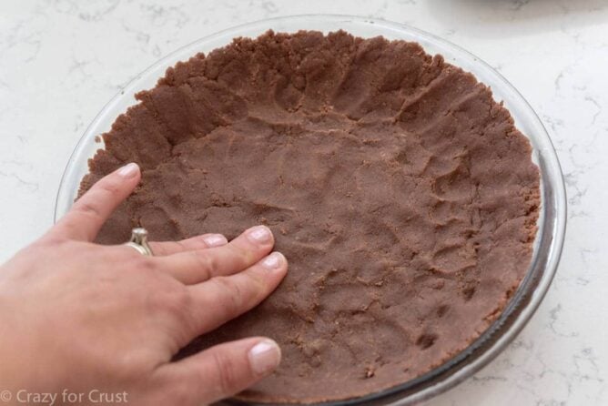No Roll Chocolate Pie Crust being pressed into a glass pie plate