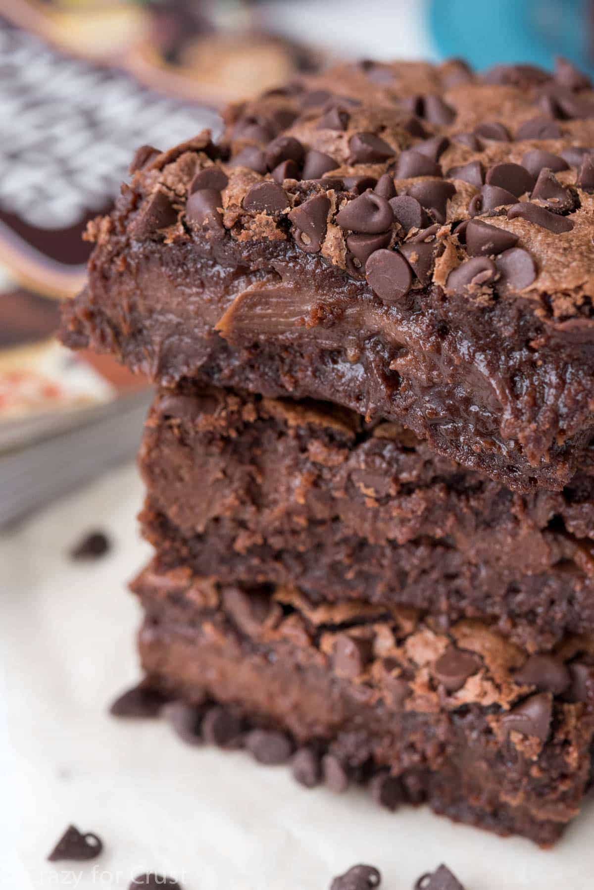 Stack of three brownie hot fudge cheesecake bars on white plate