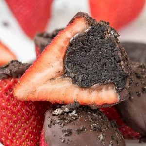 one strawberry cut in half sitting on top of four strawberries half dipped in chocolate