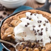 skillet chocolate chip cookie with chocolate chips and whipped cream on top and title text in top right corner