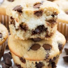 Stack of two cream cheese filled chocolate chip muffins with top muffin cut in half to show cream cheese
