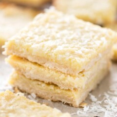 Close up shot of three gooey coconut pie bars stacked on eachother