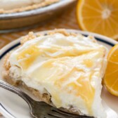 Slice of no bake lemon cheesecake on plate with fork and half a lemon