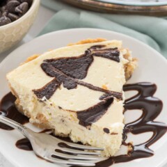 Slice of chocolate swirl cheesecake pie on white plate with silver fork