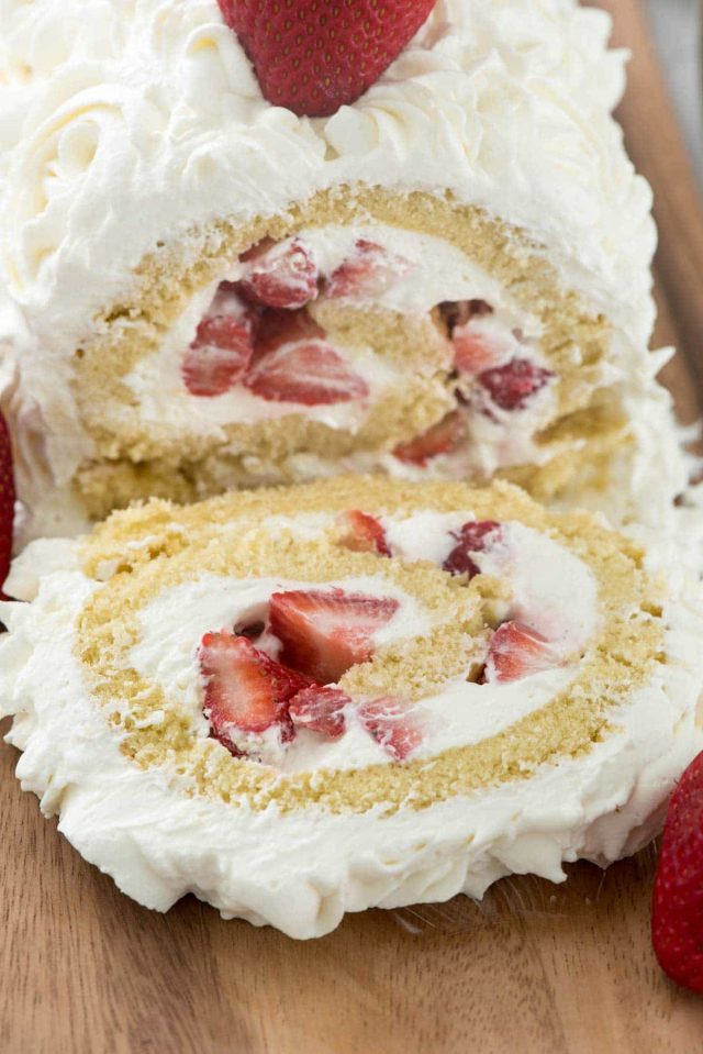 Sliced Strawberry Short cake roll on a wooden board. 