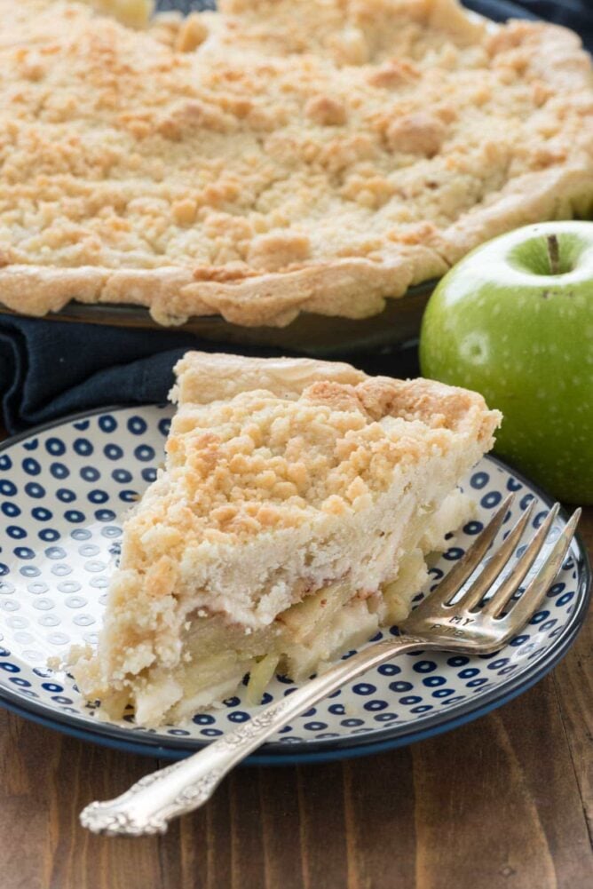 Slice of dutch apple pie on a plate with a fork.