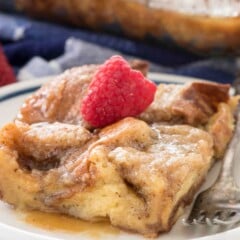 Overnight monkey bread french toast piece on a white plate with a raspberry on top