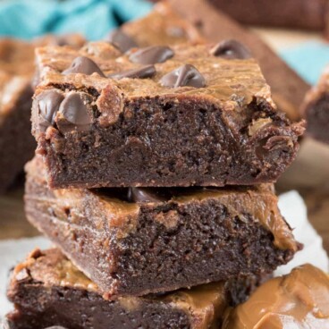 Stack of three fudgy caramel brownies on parchment paper