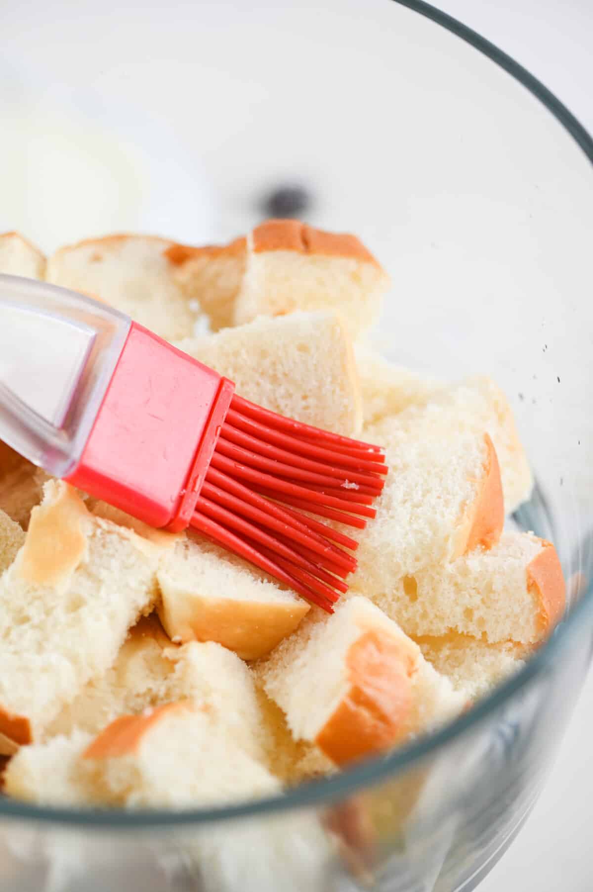 pastry brush brushing chopped dinner rolls in dish.