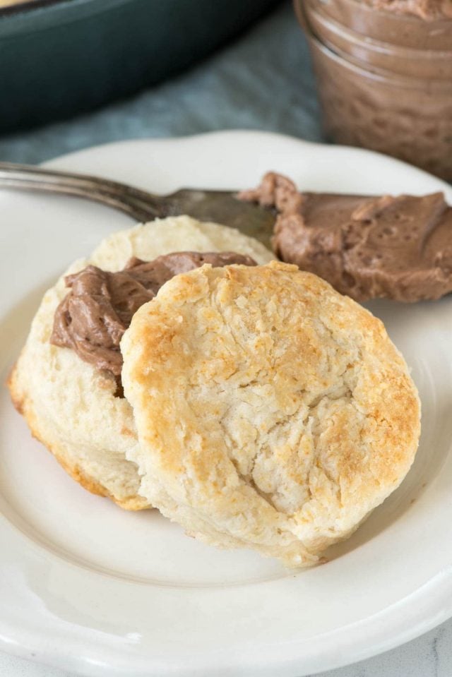 Biscuit with chocolate spread on a white plate with spread on a knife