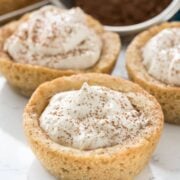 Three tiramisu cookie cups with cocoa in background