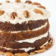 Close up of three layered naked carrot cake on white cake stand