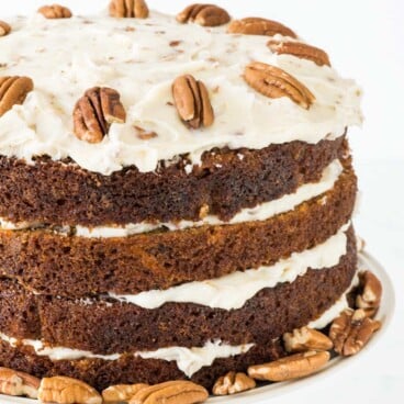 Close up of three layered naked carrot cake on white cake stand