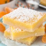 Stack of three orange dream bars with powdered sugar on top