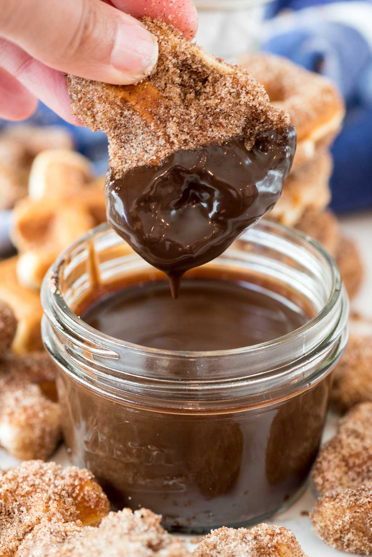 dipping churro bite in jar of ganache