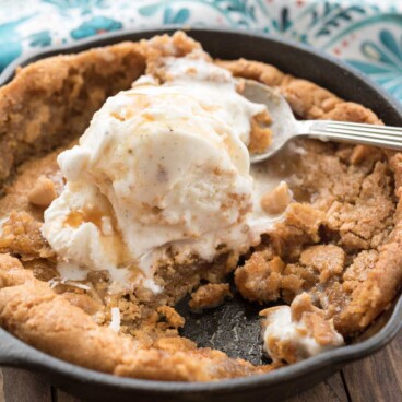 Skillet blondie in skillet with ice cream and spoon on top