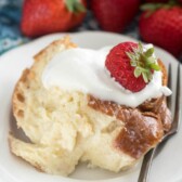 Piece of tres leches french toast casserole on white plate with fork