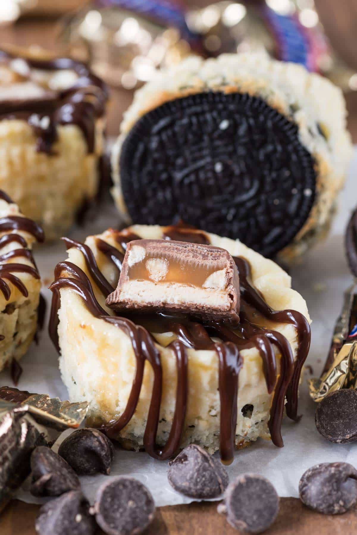 Mini Snickers Cheesecakes - these easy cheesecakes are made in a muffin cup with an Oreo crust and a surprise Snickers bite filling!