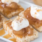 sliced Rice Krispie Treats with apple pie filling and whipped cream on top on white plate
