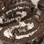 sliced Oreo cake roll thats rolled with white frosting and topped with crumbled Oreos.