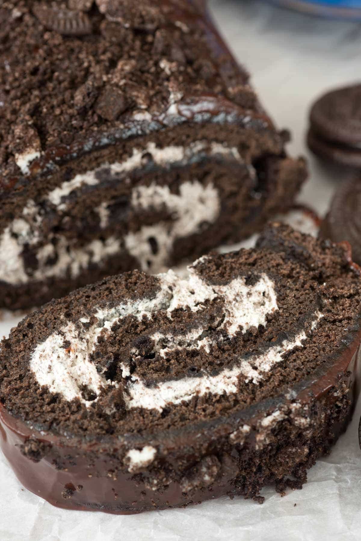sliced Oreo cake roll thats rolled with white frosting and topped with crumbled Oreos.