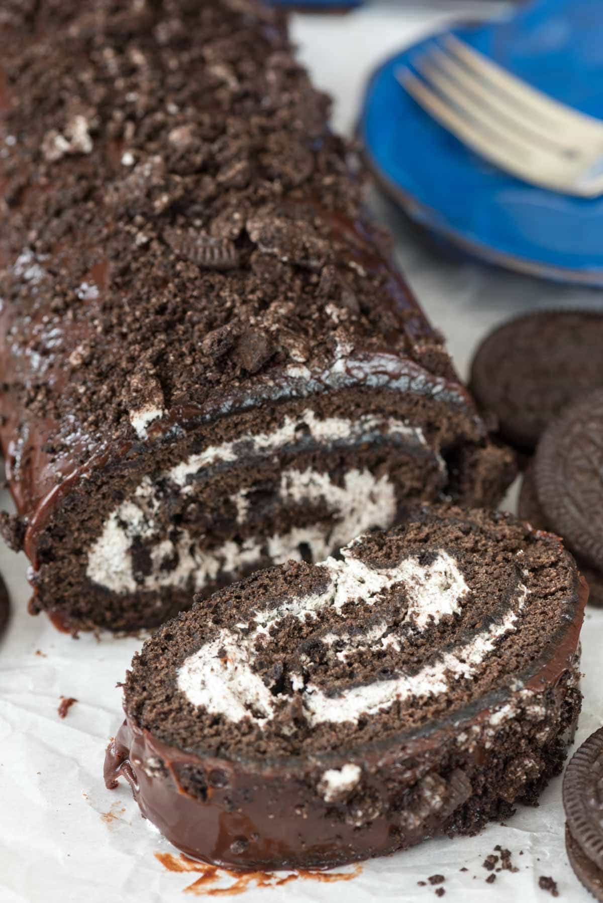sliced Oreo cake roll thats rolled with white frosting and topped with crumbled Oreos.